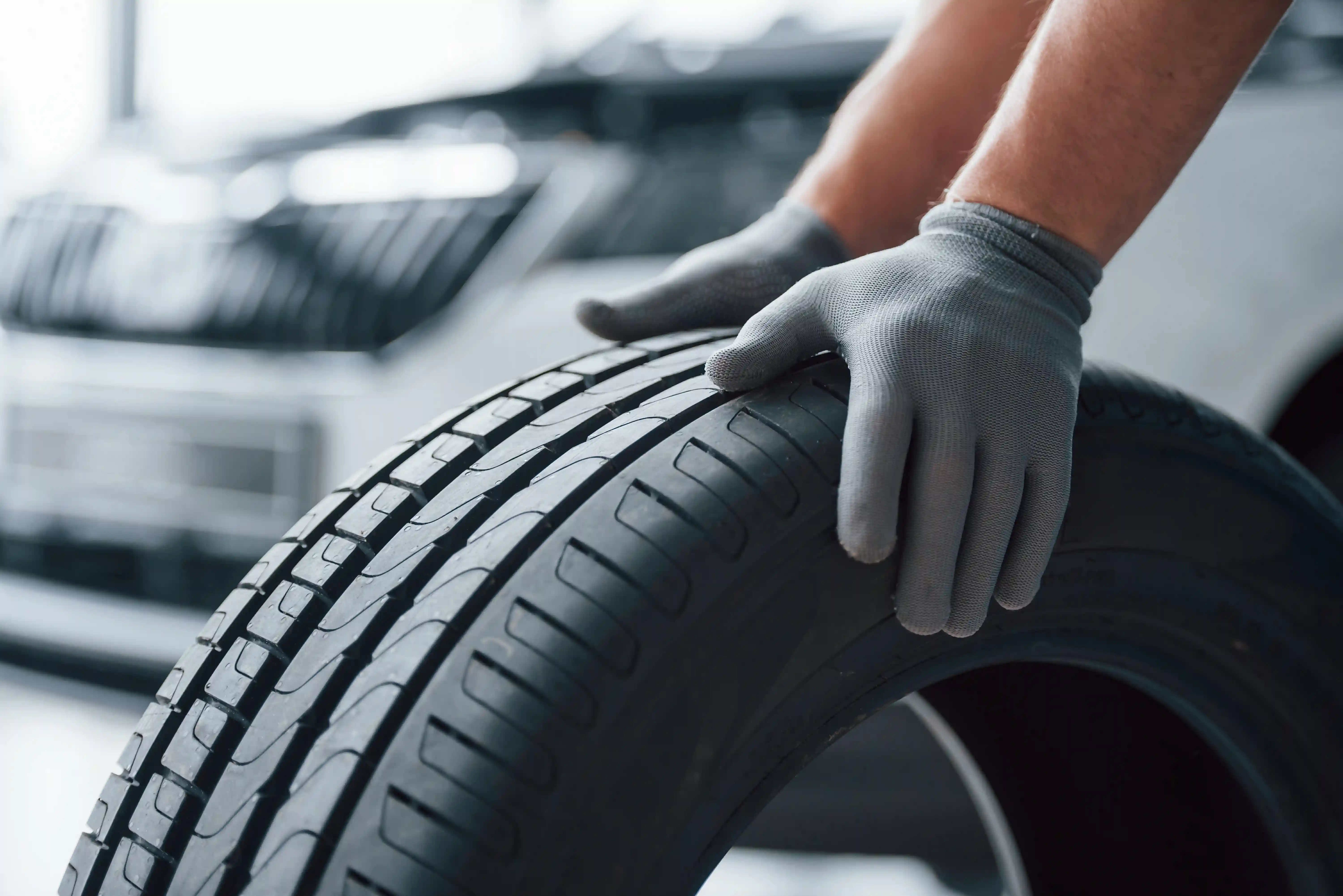 mechanic holding tire using gloves