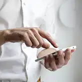 man in white shirt holding a phone